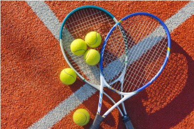 Zwei Tennisschläger und drei Tennisbälle auf einem Tennisplatz.